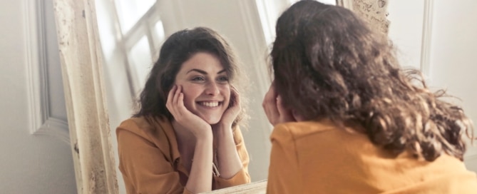 Happy Woman Looks in Mirror